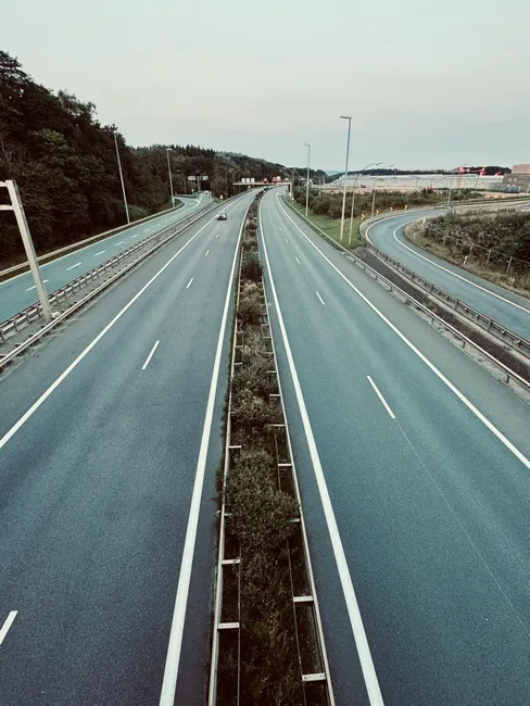 Aerial view of an empty highway with a greenery divider at dusk, ideal for travel and transportation themes.