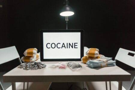 Staoueli : la police d’Alger saisit 3,15 kg de cocaïne Cocaine word on tablet with bags of drugs in a dimly lit room.