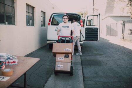 Volunteers unloading aid boxes with essential supplies like food and medicine.