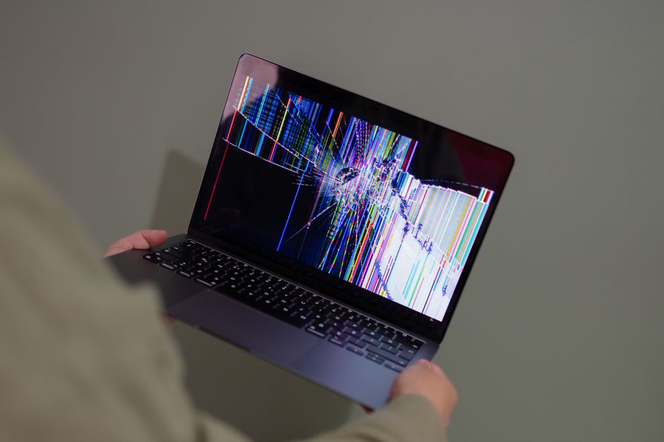 Leboncoin affiche une erreur technique : la piste du Mac A broken laptop screen displayed with colorful glitch being held by a person.