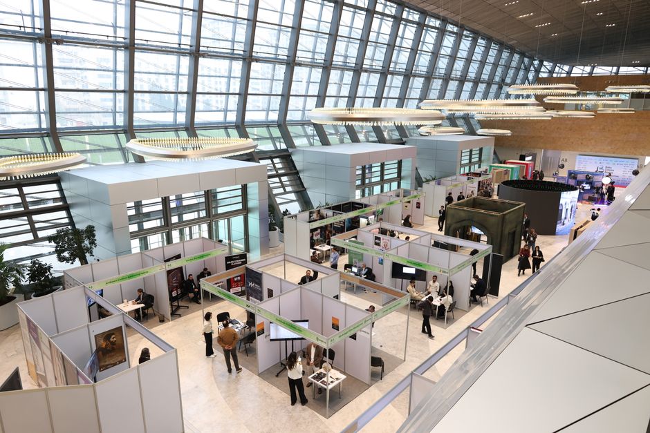 À Vérone, le marbre algérien vise le marché chinois A bustling trade show exhibition inside a modern hall with people networking and exploring booths.
