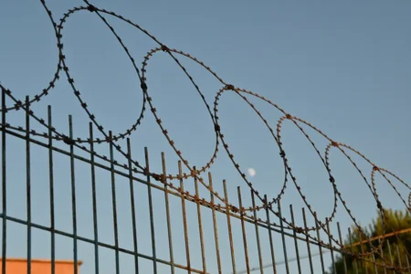 Ceuta : des appels à un passage collectif le 23 septembre A close-up view of a barbed wire fence under a clear blue sky, suggesting protection and security.