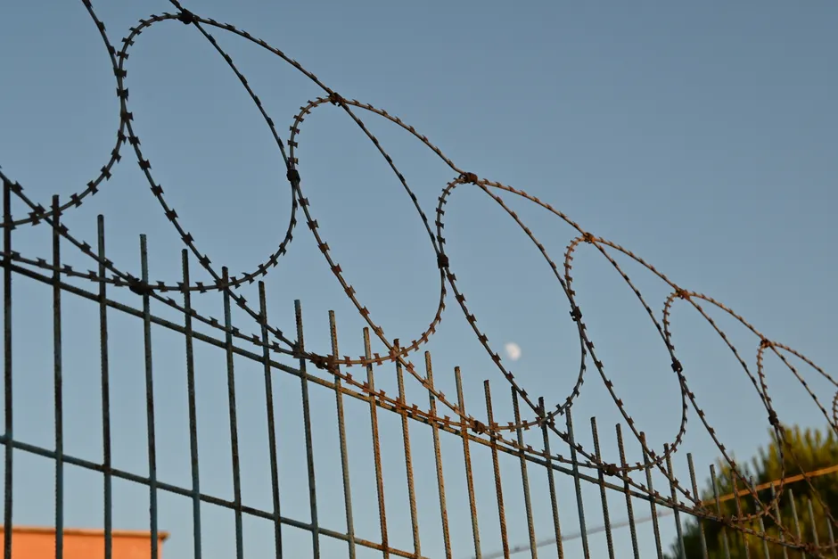 Ceuta : des appels à un passage collectif le 23 septembre A close-up view of a barbed wire fence under a clear blue sky, suggesting protection and security.