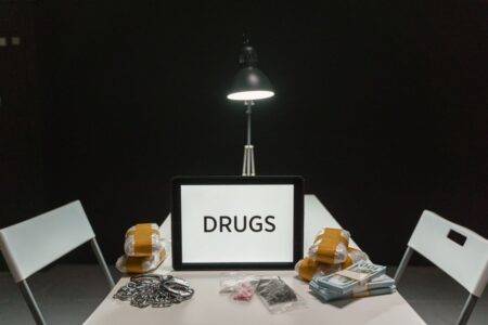 A dimly lit room with a sign displaying 'DRUGS' surrounded by money and illegal substances.