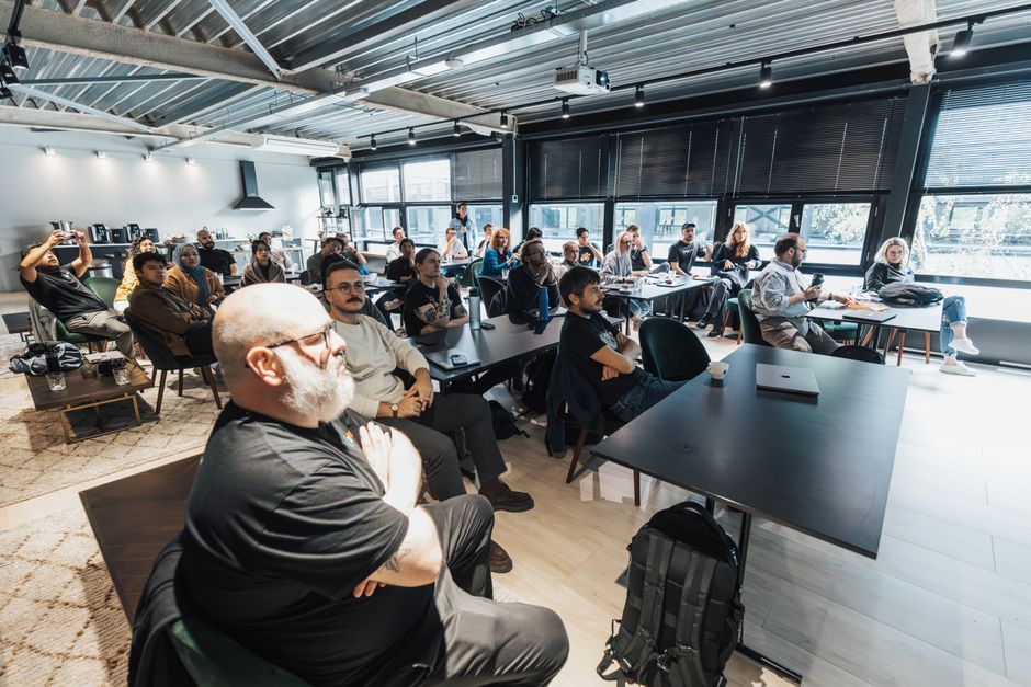 Algérie : une commission pour relier industrie et startups A diverse group of professionals attentively listening during an indoor business meeting in a modern conference room.