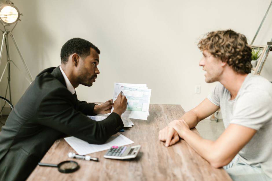 Mourabaha automobile : le BNA clarifie sa publication A financial advisor discusses paperwork with a client at a desk in a modern office.
