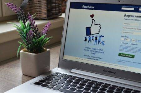 Gmail : connexion, récupération et sécurité du compte A Lenovo laptop displaying Facebook login beside a lavender plant indoors.