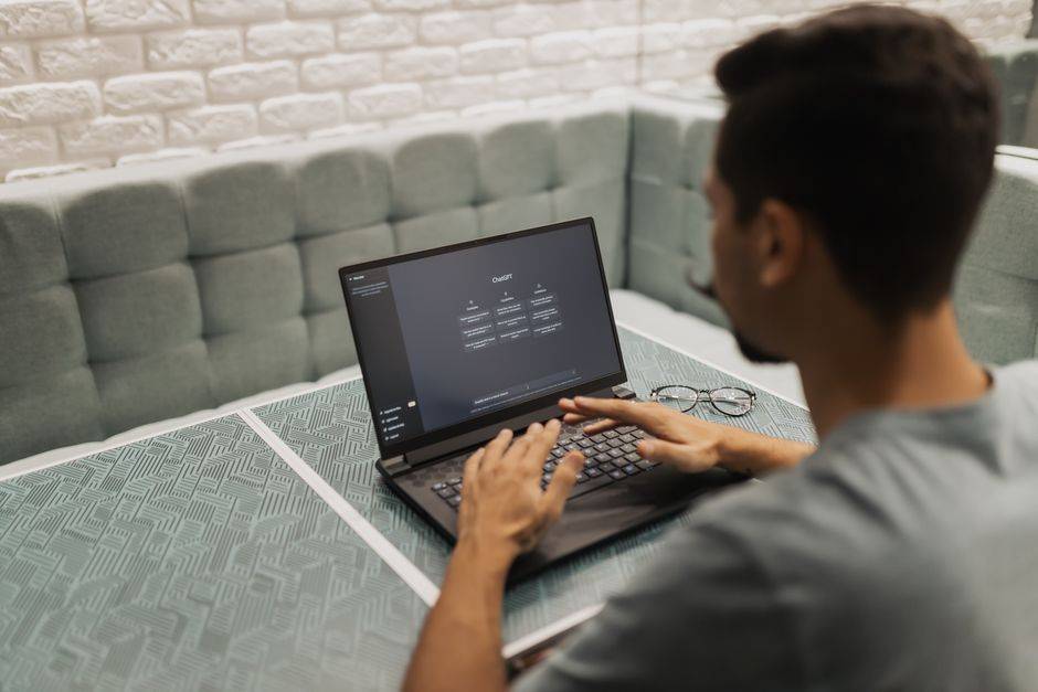 Quand l’IA reconstitue un souvenir des années 80 A man working on a laptop in a cozy, modern office space with a focus on technology.
