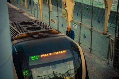 Métro d’Alger : la liaison directe reprend le 21 septembre 2026 A metro train at Istanbul station with a man waiting on the platform, showcasing urban transport.
