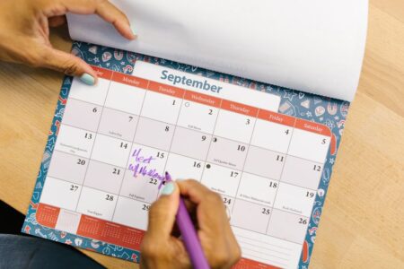 Pourquoi le temps qui passe semble accélérer avec l’âge A person marking a calendar in September with a purple pen on a wooden desk.