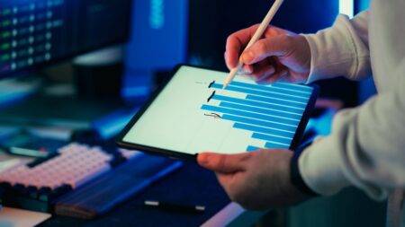 Outils SEO IA en 2026 : choisir selon son usage A person using a stylus on a tablet showing a business graph in an office setting.