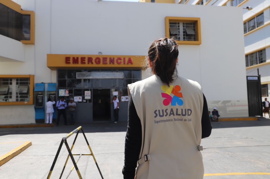 A SUSALUD official outside an emergency entrance at a hospital during the day.