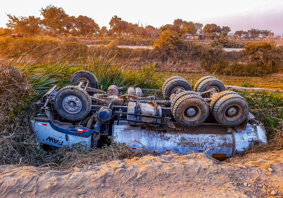 Accident à Touggourt : deux morts et un adolescent blessé A truck overturned by the roadside on a rural dirt path during daytime.