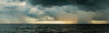 Pluies orageuses en Algérie : 21 wilayas en vigilance le 18 septembre 2026 A vast ocean under stormy skies with dramatic dark clouds and rainfall.