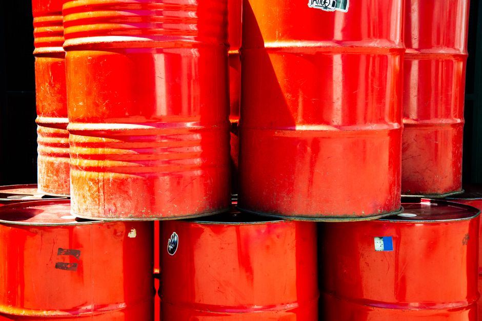 Pétrole algérien : le Sahara Blend à 94,32 dollars Bright red industrial oil barrels stacked outdoors in daylight, showcasing vivid color and industrial theme.