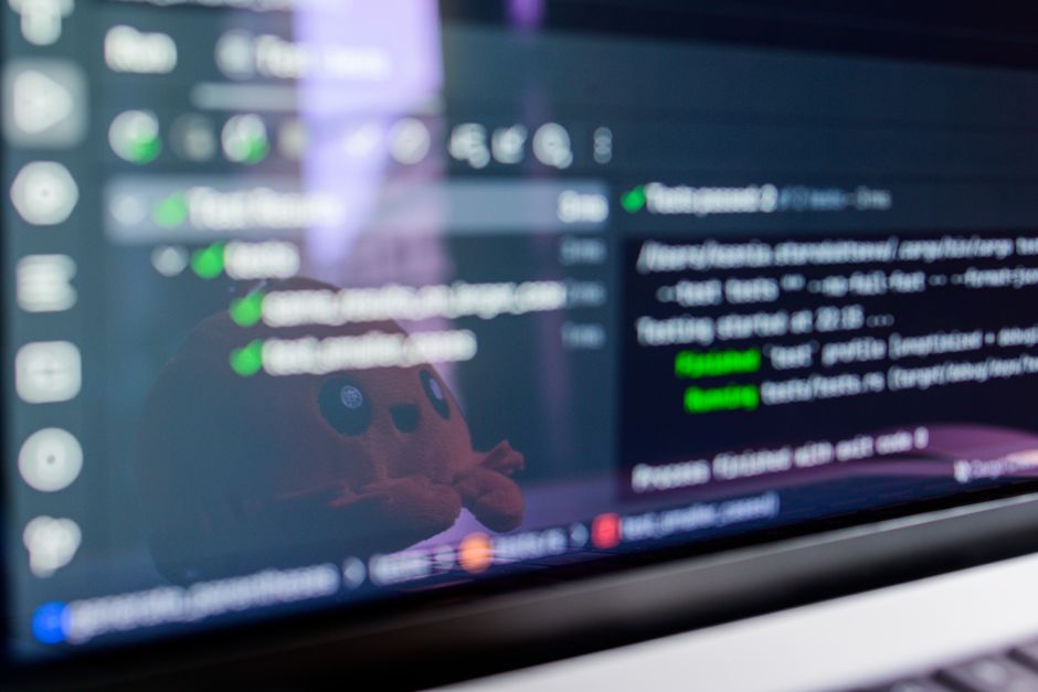 Claude Desktop : installation, modes et permissions Close-up of a laptop screen displaying programming code with a cute plush toy reflecting.