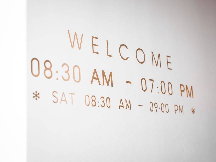 Algérie-Émirats : les 48 heures au cœur de la rupture Close-up of a minimalist welcome sign displaying business hours in stylish typography.