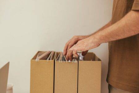 Algérie : 42 promotions dans trois corps des collectivités locales Close-up of a person organizing files in cardboard boxes, ideal for business and office themes.