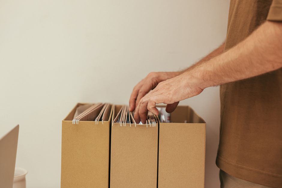 Algérie : 42 promotions dans trois corps des collectivités locales Close-up of a person organizing files in cardboard boxes, ideal for business and office themes.