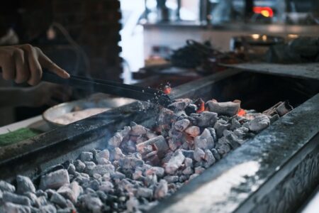 À Tlemcen, Hadja Yamina cuisine sur des braises au palais El Mechouar Close-up of grilling meat on glowing embers in a barbecue setup, outdoors in Diyarbakır.