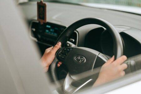 Close-up view of hands holding the steering wheel inside a car.