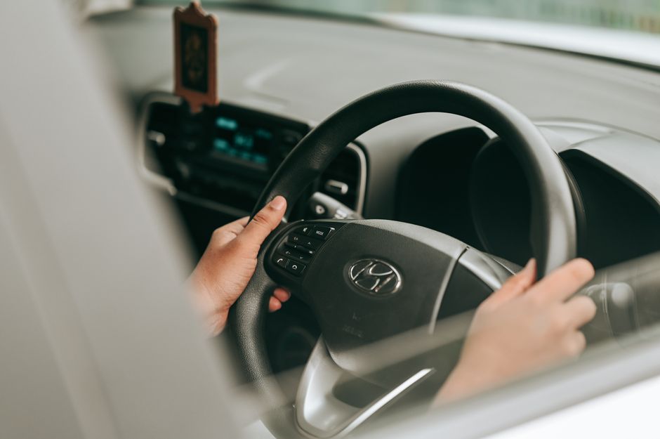 Voitures sans volant : quelles preuves avant la confiance? Close-up view of hands holding the steering wheel inside a car.