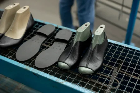 PEAK prépare une unité de chaussures à Blida pour l’export Detailed view of shoe making process with leather uppers and molds on work table.