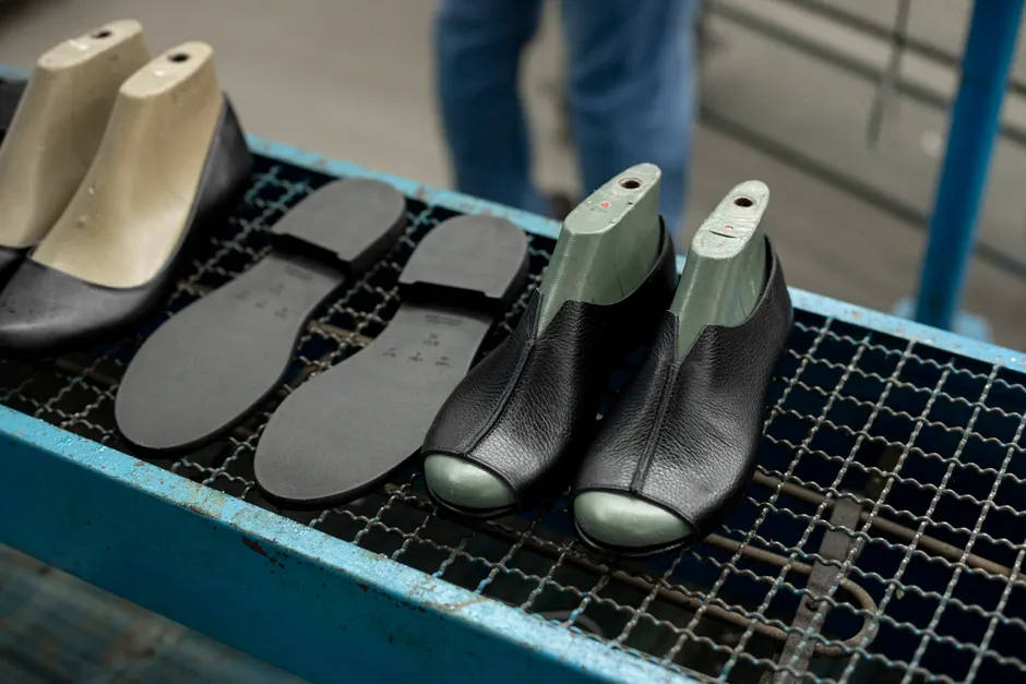 PEAK prépare une unité de chaussures à Blida pour l’export Detailed view of shoe making process with leather uppers and molds on work table.