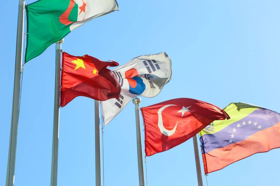 Algérie-Émirats : une rupture après des tensions accumulées Five national flags from different countries waving on flagpoles under a clear blue sky