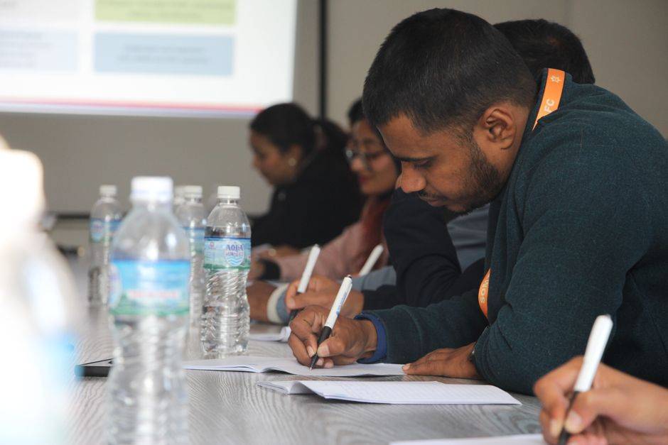 Algérie : un master professionnel en finance islamique Focused students taking notes during a classroom seminar indoors.