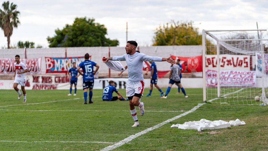 Football player celebrating goal during a match outdoors with teammates and opponents nearby.