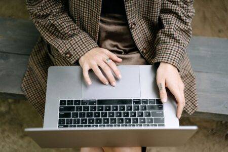 TalkTalk Mail : retrouver ses e-mails, étape par étape High angle view of individual using a laptop on a wooden bench while wearing a checkered coat.