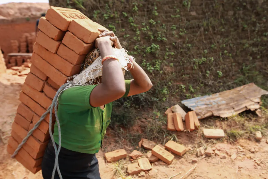 Inde : un employé aurait été attaché après une faible connexion internet Indigenous worker carrying bricks on head with rope outdoors.