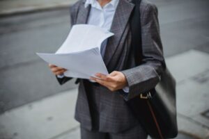 Professional businesswoman reviewing documents outdoors in a city environment.