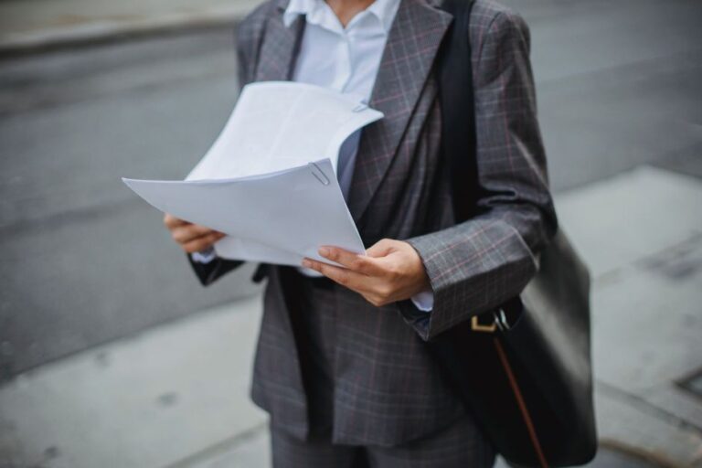 Professional businesswoman reviewing documents outdoors in a city environment.