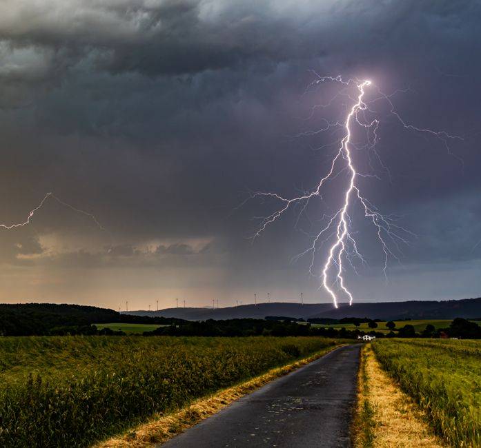 Pluies orageuses en Algérie : les 50 wilayas concernées le 9 septembre Striking landscape with a lightning bolt hitting near a rural road under a stormy sky.
