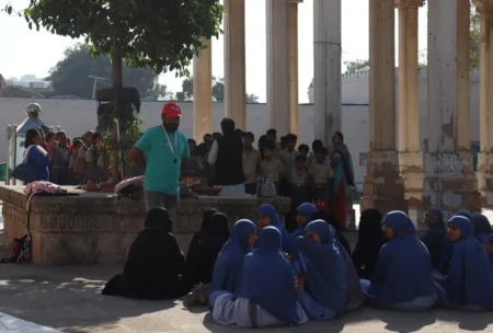 Students in uniforms visiting a historical site with columns and shadows. Education and culture.