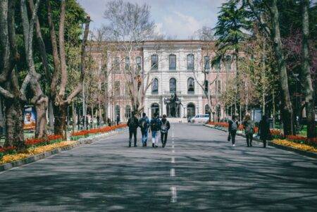 Algérie : 1 884 839 étudiants et 13 nouvelles spécialités Students walking on a university campus surrounded by trees and spring flowers.