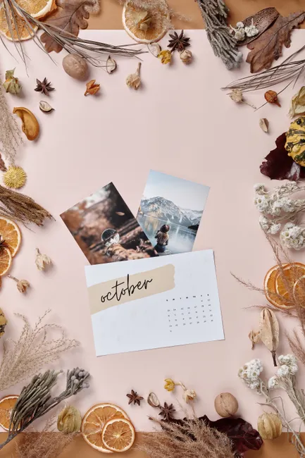 Stylish October flatlay featuring autumn leaves, dried plants, and a decorative calendar.