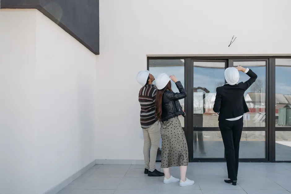 Rentrée scolaire 2026-2027 : les wilayas vérifient les écoles Three architects evaluating exterior building structure, wearing helmets and business attire.