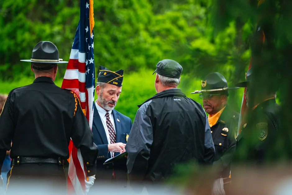 Uniformed individuals gather with USA flag, engaging in official outdoor ceremony.